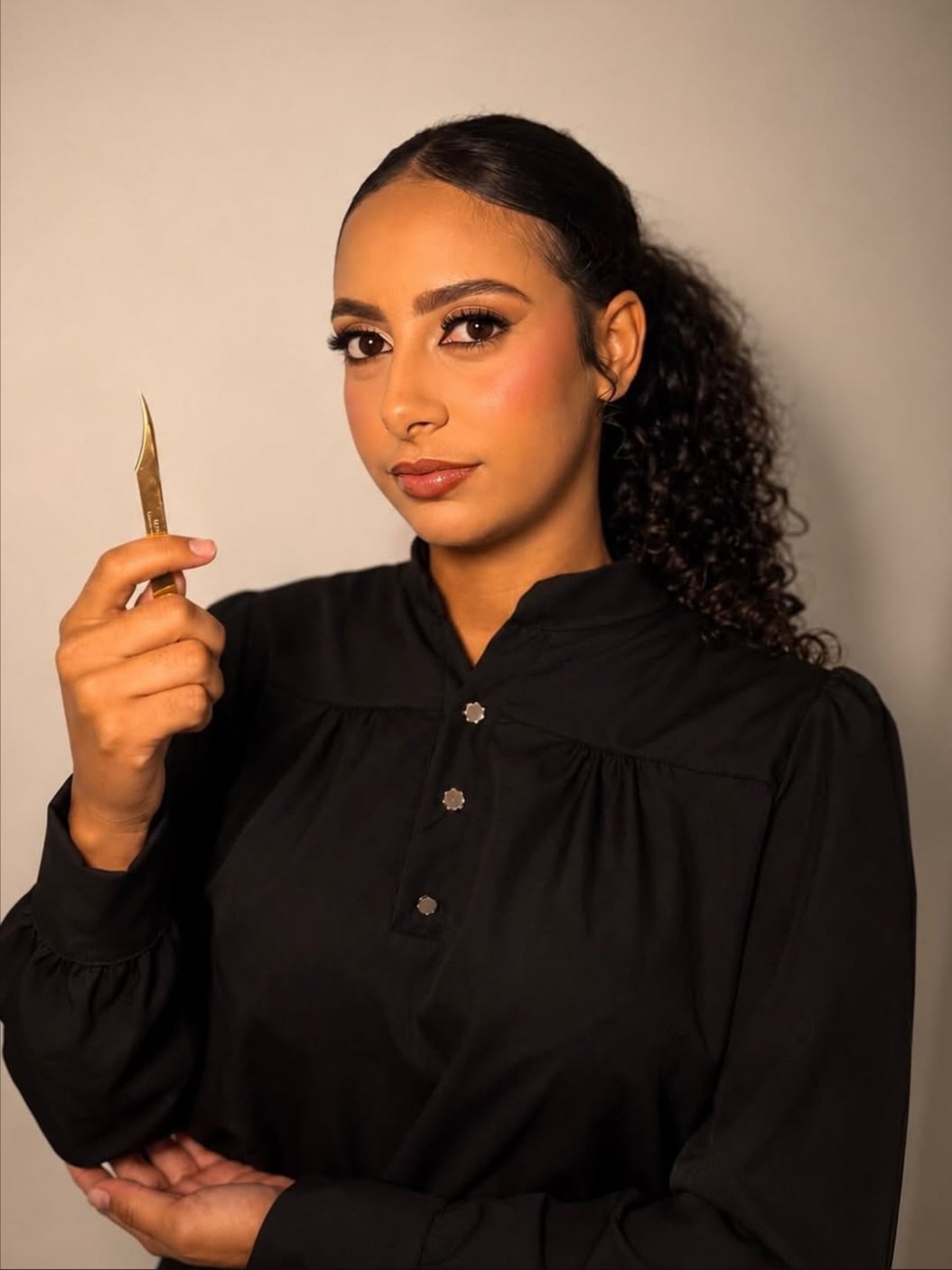 Kayllanne Feitosa, lash designer, segurando uma pinça dourada
